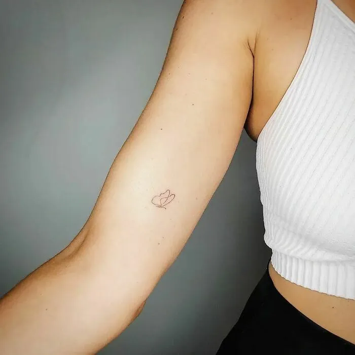 Fine-line single tattoo of a small heart on an arm, showcasing minimalist artistry.