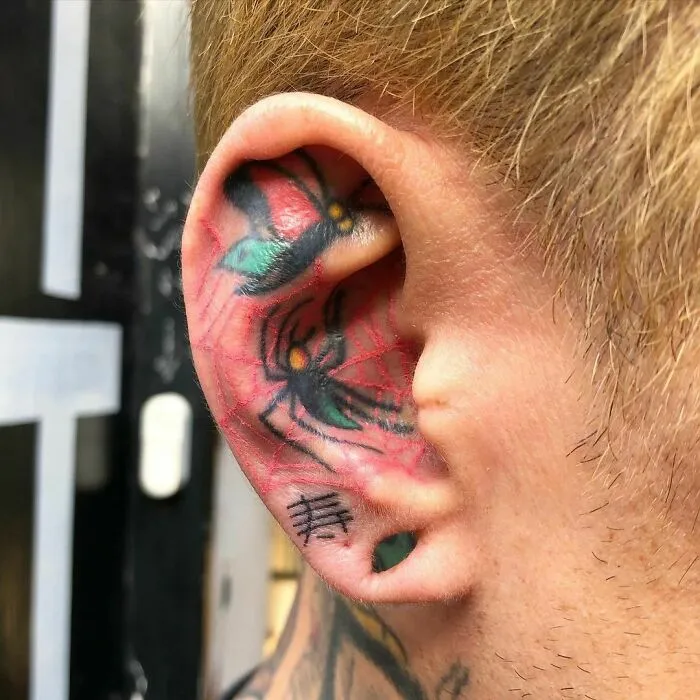 Colorful spider web ear tattoo with flower details.