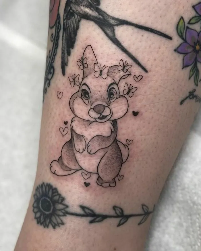 Cartoon tattoo of a cute rabbit surrounded by hearts and flowers, inspired by an all-time favorite animated show.
