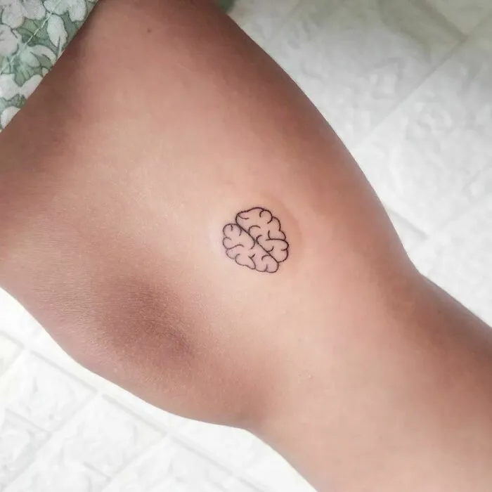 Minimalist brain tattoo on inner arm, showcasing an aesthetically pleasing design.