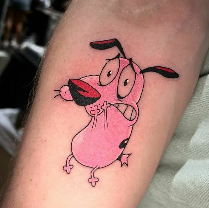 Cartoon tattoo of Courage the Cowardly Dog on arm, showcasing colorful nostalgia artwork.