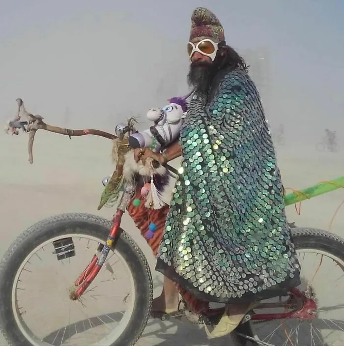 Male riding a bike with pony wearing sparkly coat 