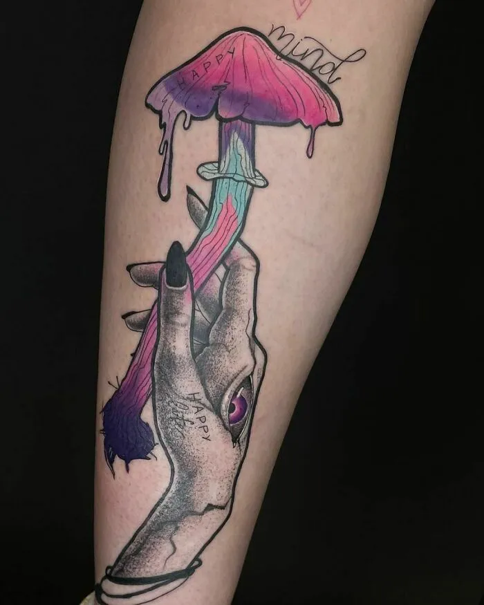 Vibrant watercolor tattoo of a hand holding a colorful mushroom on an arm.