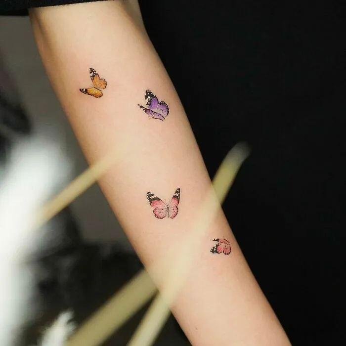 Watercolor butterfly tattoos on forearm, showcasing beautiful ink art.