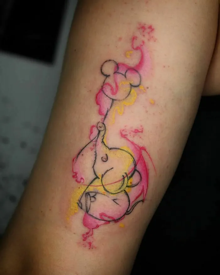 Colorful elephant watercolor tattoo on arm with pink and yellow splashes.