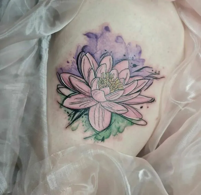 Watercolor tattoo of a pink lotus flower with purple and green accents, showcasing beautiful inkspiration.