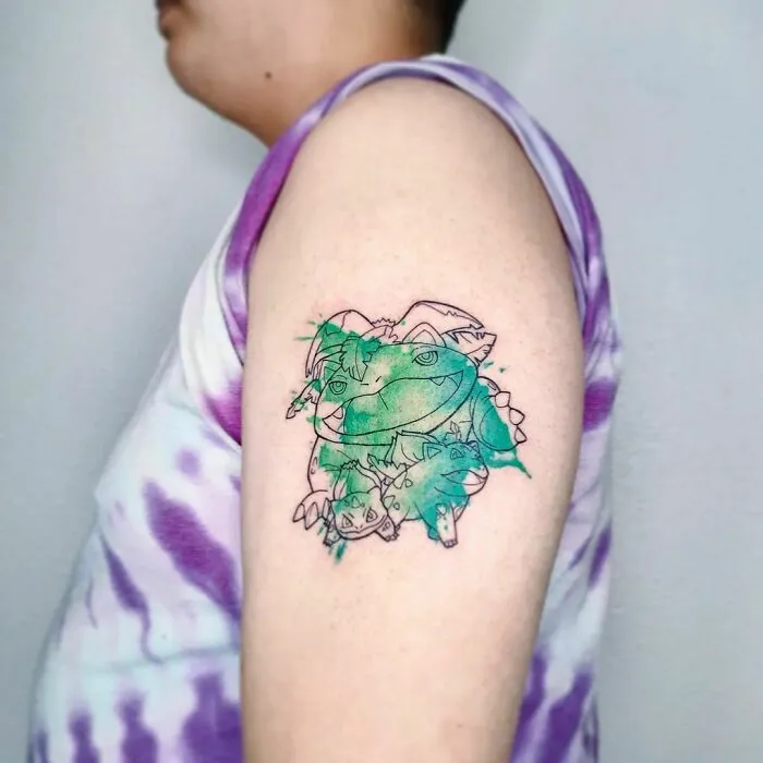 Watercolor tattoo on arm featuring a green and purple design with abstract elements.