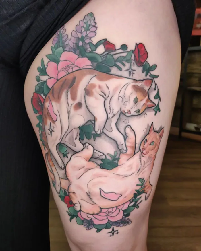 Colorful cat tattoo with flowers celebrating the animal kingdom on a thigh.