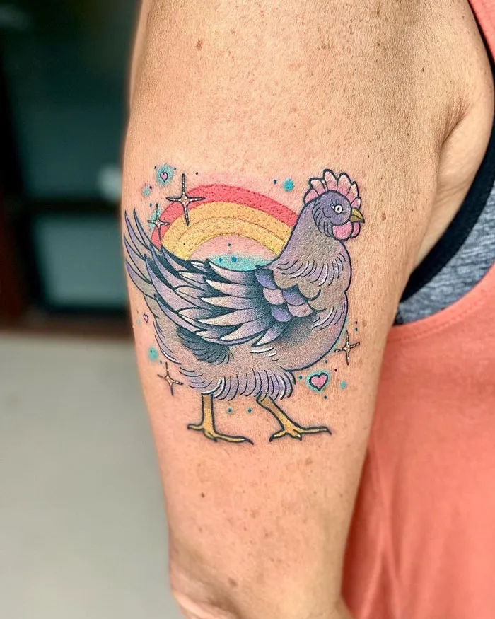 Colorful chicken tattoo on arm with rainbow background, celebrating the animal kingdom.