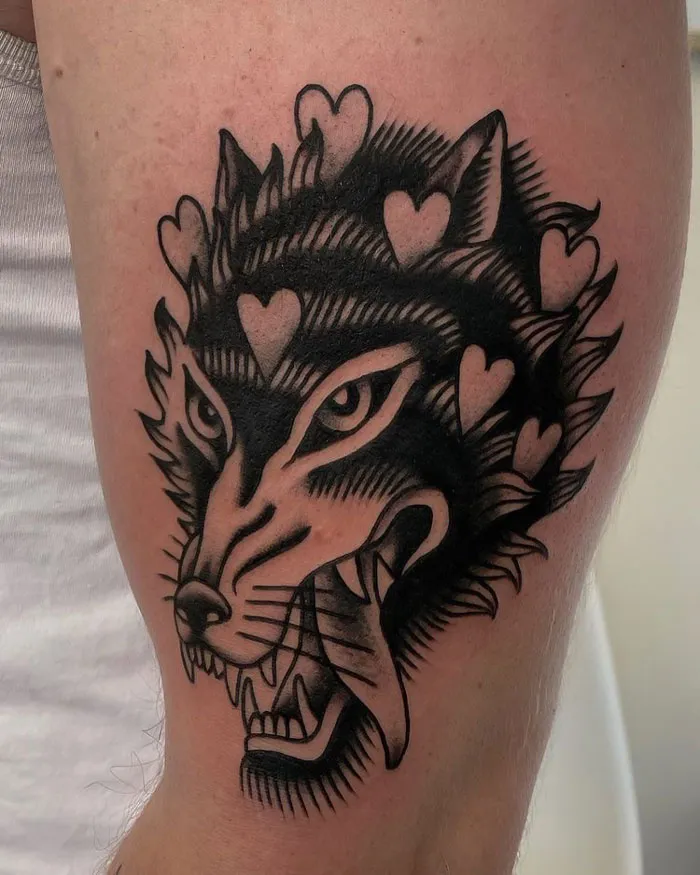 Tattoo of a fierce wolf head adorned with hearts, celebrating the animal kingdom on a person's arm.