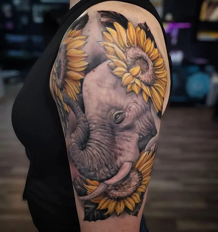Elephant tattoo with sunflowers in a realistic and simple design on a person's arm.