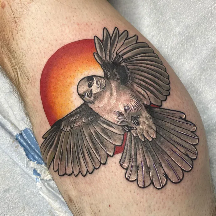 Realistic bird tattoo with open wings against a colorful sun background, showcasing simple animal art.