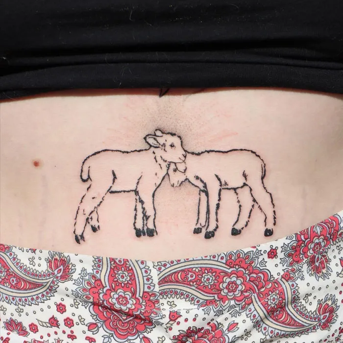 Minimalist tattoo of two lambs embracing on lower back, showcasing simple and realistic animal design.