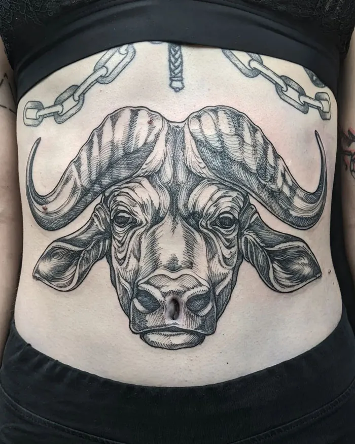 Buffalo head tattoo on a person's torso, showcasing detailed artistry celebrating the animal kingdom.