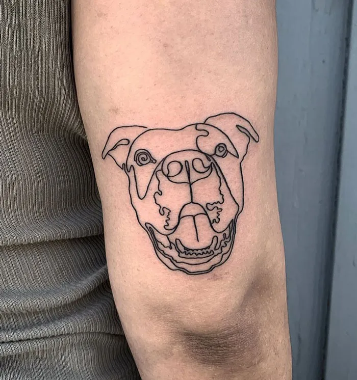 Line art dog tattoo on arm, showcasing animal tattoo simplicity and realism.