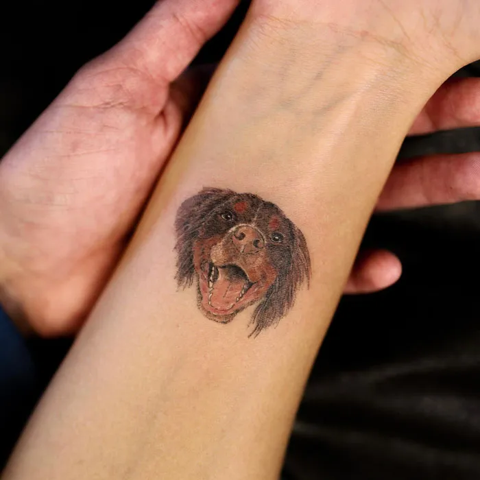 Animal tattoo on forearm depicting a dog's face, showcasing artistic detail and celebrating the animal kingdom.
