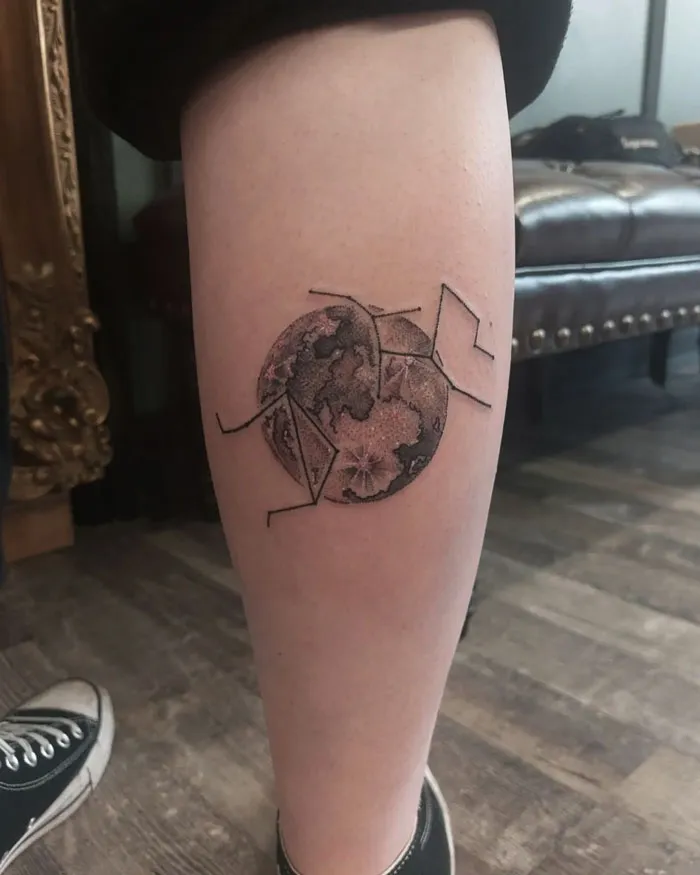 Unique calf tattoo featuring an abstract geometric design with circular elements, displayed on a person's leg.