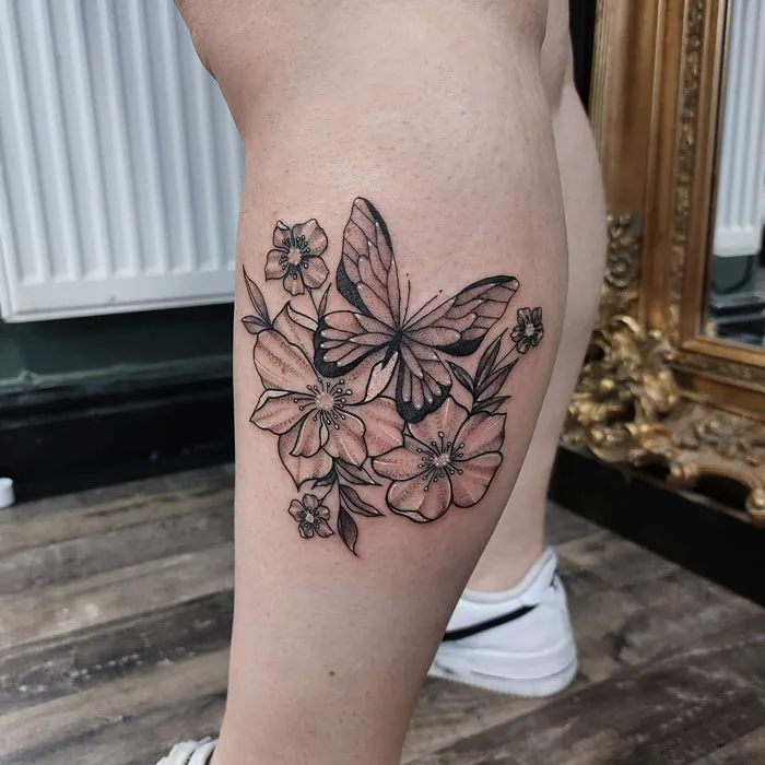 Butterfly and floral lower leg tattoo design in black ink.