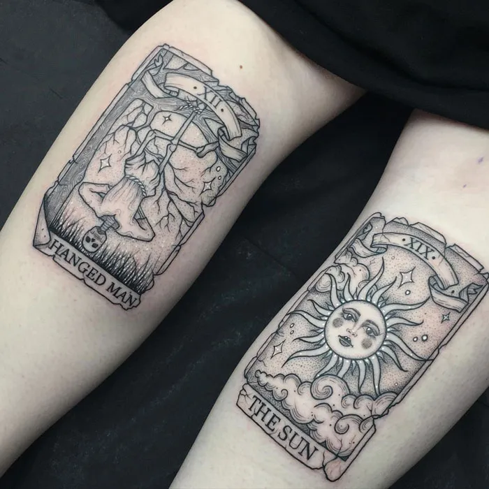 Tarot-inspired calf tattoos featuring The Hanged Man and The Sun cards, showcasing coolness and creativity.