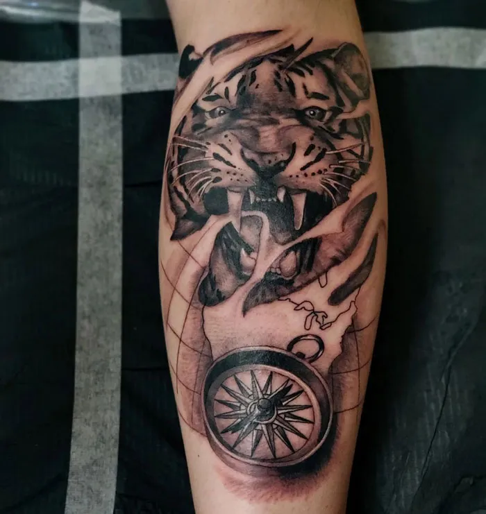 Tiger and compass design on calf tattoo, showcasing intricate details and bold lines.