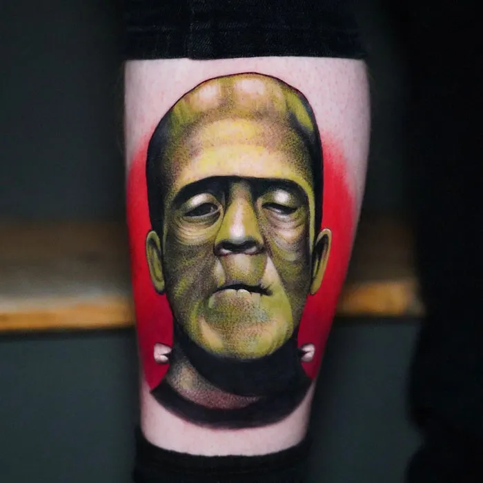 Unique calf tattoo featuring a vibrant Frankenstein's monster design against a bold red background.