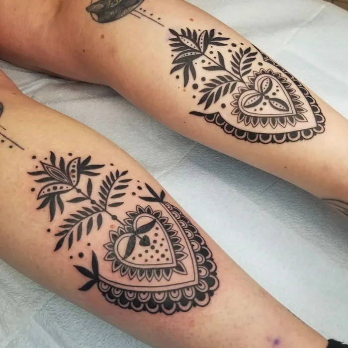 Lower leg tattoos featuring intricate heart and leaf designs on the calves.