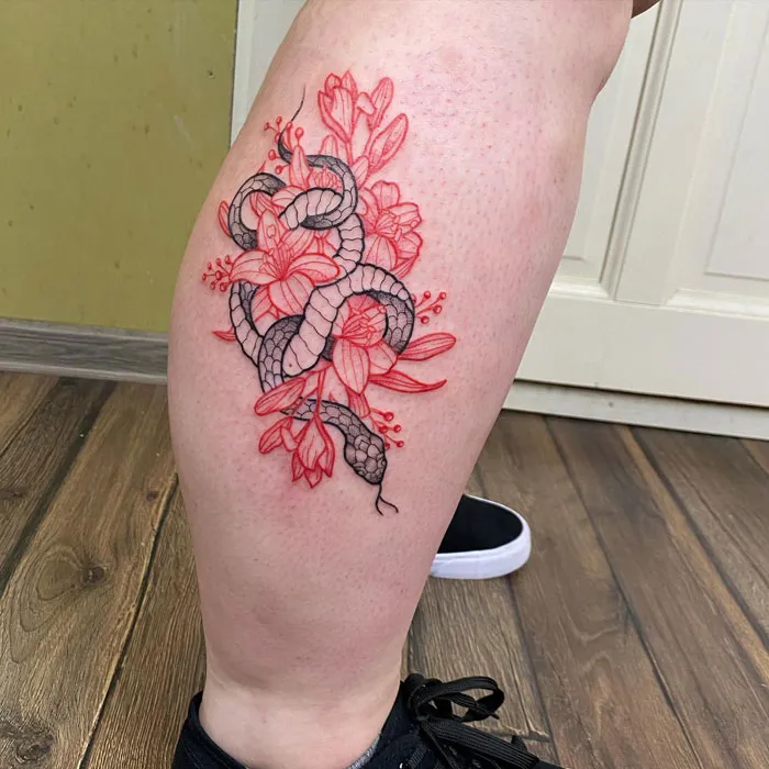 Lower leg tattoo featuring a snake entwined with blooming flowers in red and black ink.