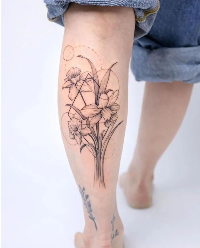 Delicate floral calf tattoo design showcasing daffodils in black ink, epitomizing coolness and artistic flair.