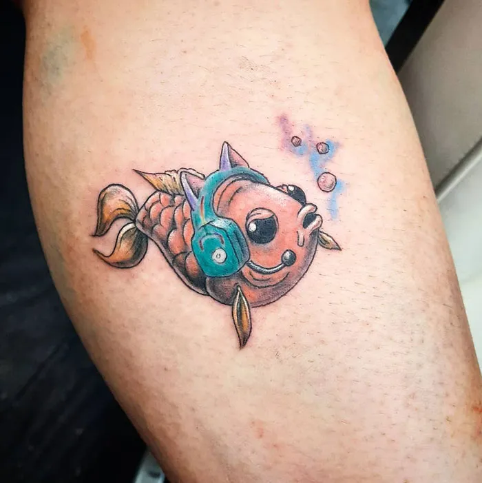 Lower leg tattoo of a colorful fish with headphones, emitting bubbles.