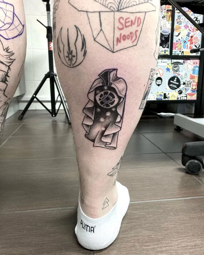 Unique calf tattoo featuring an abstract, cape-wearing figure with geometric elements.