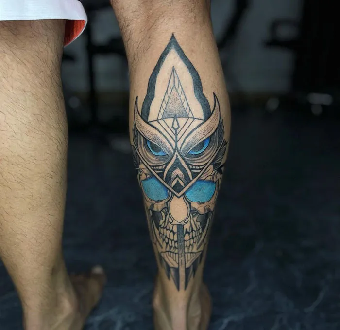 Stylized owl tattoo design on a lower leg showcasing intricate details and bold colors.
