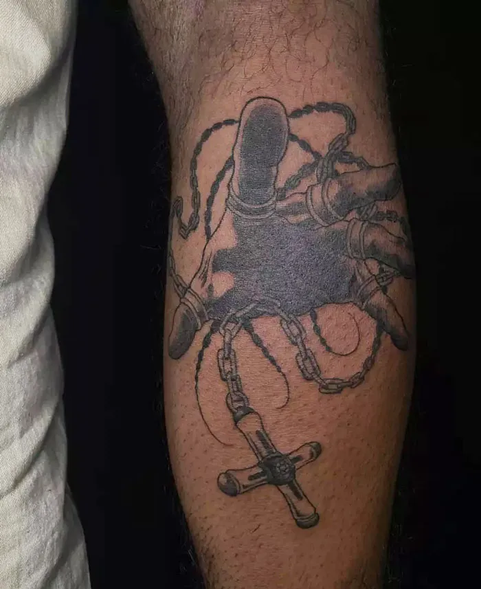 Calf tattoo featuring a realistic hand holding chains, showcasing intricate details and pure coolness.