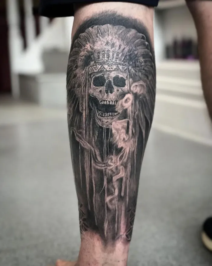 Calf tattoo featuring a detailed skull with a headdress, showcasing cool and intricate design.