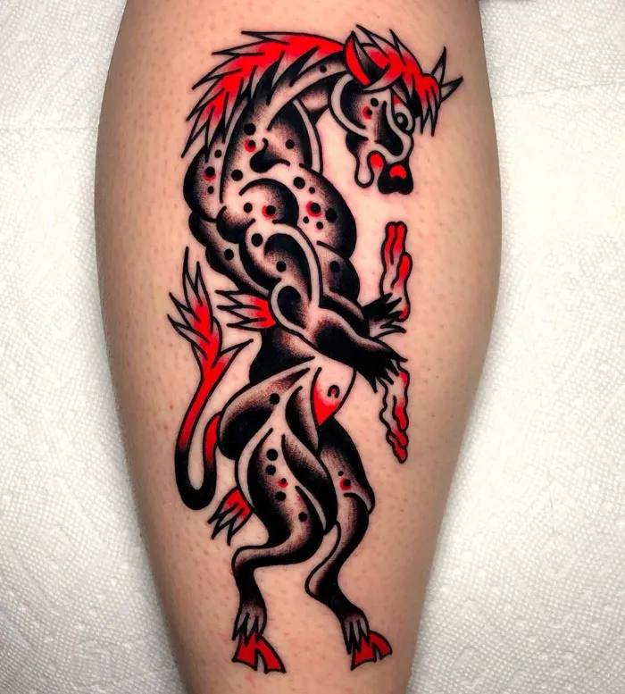 Calf tattoo featuring a unique, stylized mythical creature in vibrant black and red design.
