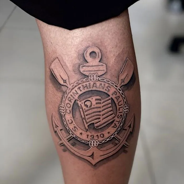 Unique calf tattoo featuring a detailed emblem with anchor and oars design.