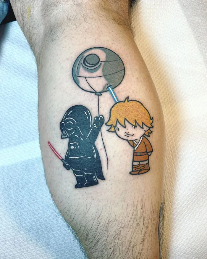 Calf tattoo featuring cartoon-style characters, including a black figure with a balloon and a character in an orange outfit.