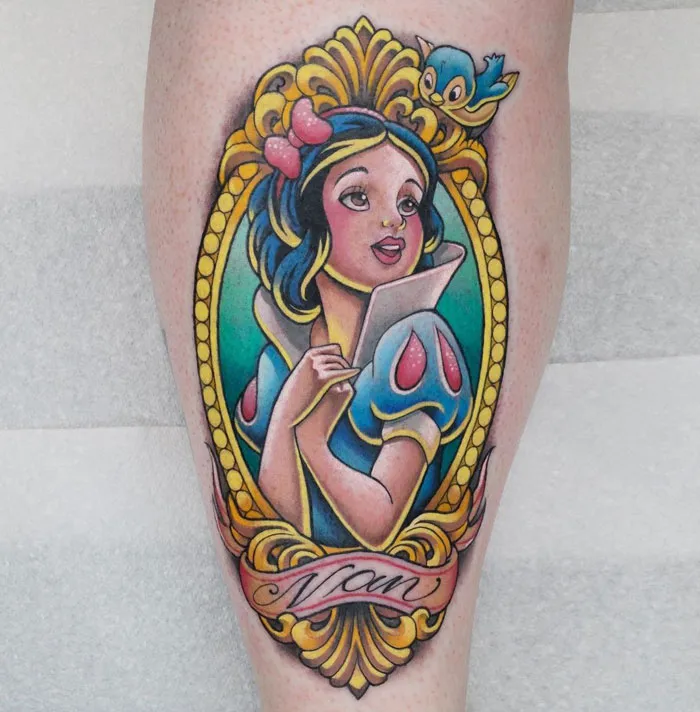 Colorful princess-themed calf tattoo with decorative frame and a bird, showcasing cool tattoo design.