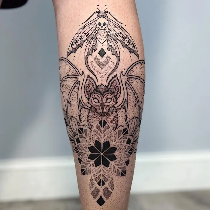 Intricate calf tattoo featuring a stylized bat and geometric patterns, showcasing coolness in detailed black ink.