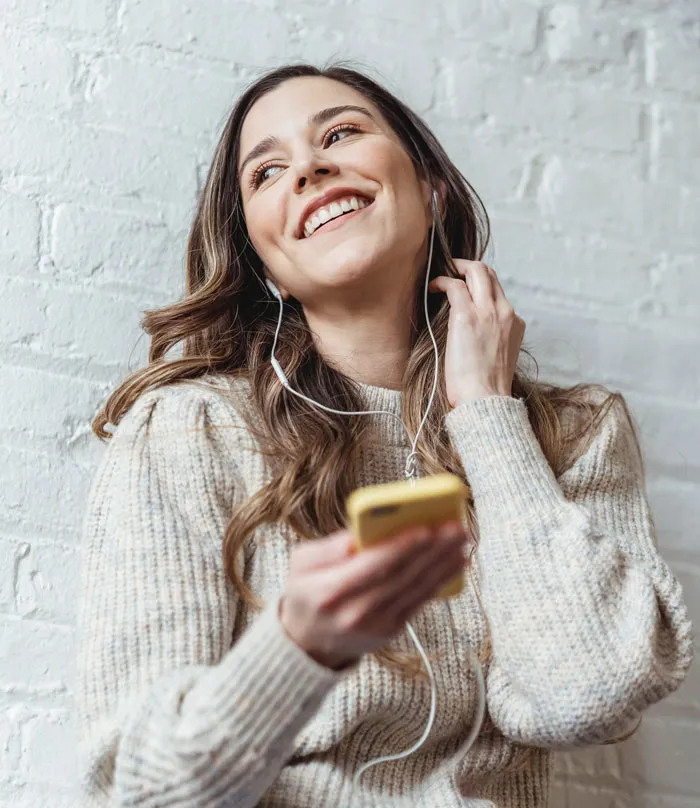 Smiling woman with headphones enjoying music at home, avoiding boredom.