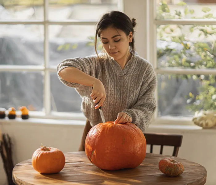 Person carving a pumpkin at home, a fun activity to avoid boredom indoors.