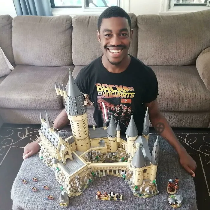 Man smiling behind a detailed LEGO build of a castle, showcasing one of these incredible LEGO builds as works of art.