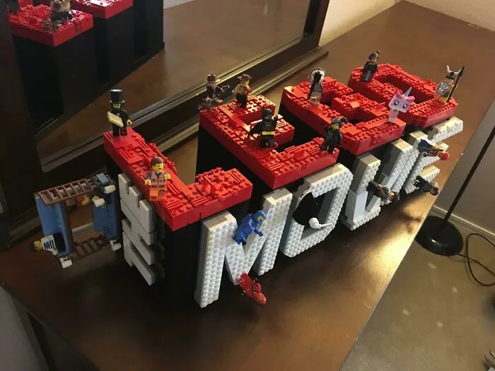 LEGO builds spelling LEGO with mini figures on top displayed on a wooden surface, showcasing incredible LEGO builds art.
