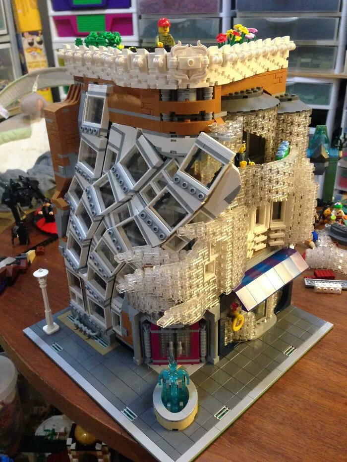 Intricate LEGO build of a modern architectural structure featuring transparent and angled elements on a tabletop display.