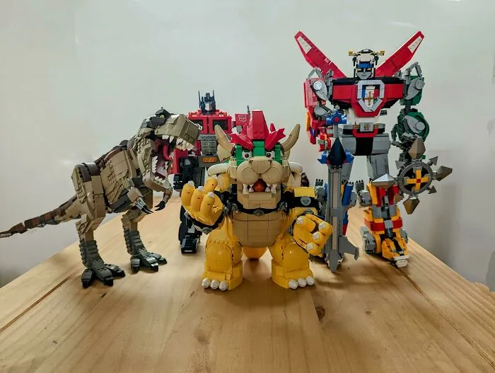 LEGO builds showcasing a dinosaur, robot, and characters in detailed and creative designs on a wooden surface.