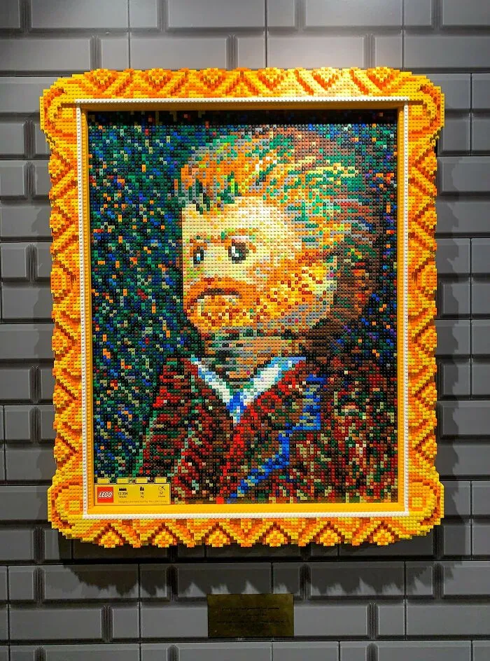Pixelated portrait made of LEGO bricks with an intricate orange frame showcasing incredible LEGO builds as art.