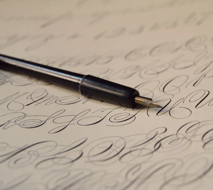 Calligraphy practice with fountain pen on paper, showcasing fun things to do at home.
