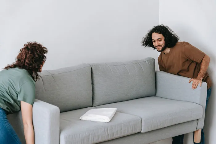 Couple rearranging a gray couch at home for fun indoor activity.