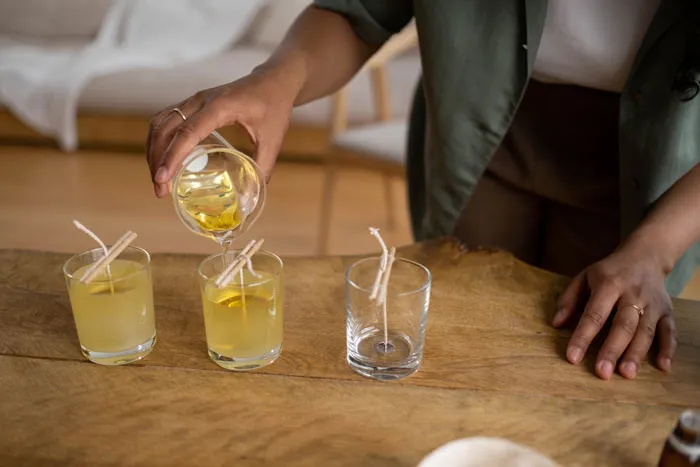 Person crafting homemade candles on a wooden table to enjoy fun things to do at home.