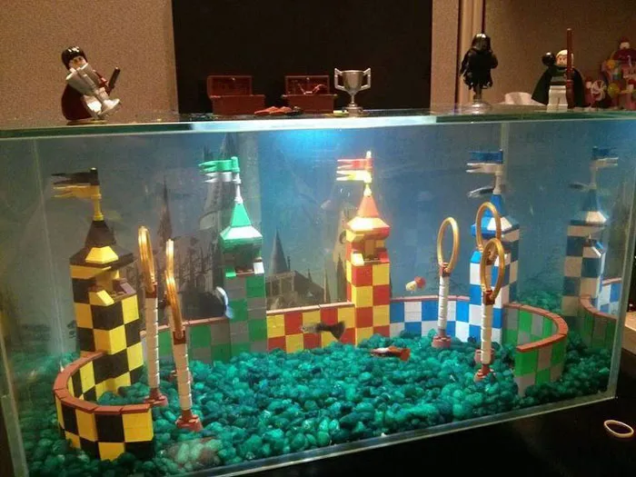 Colorful LEGO builds resembling a Quidditch stadium with towers, rings, and flags displayed inside a glass case.