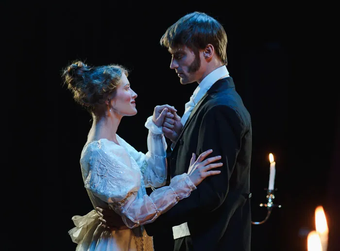 Couple in period costumes sharing an intimate dance, illuminated by candlelight, capturing a fun activity at home.